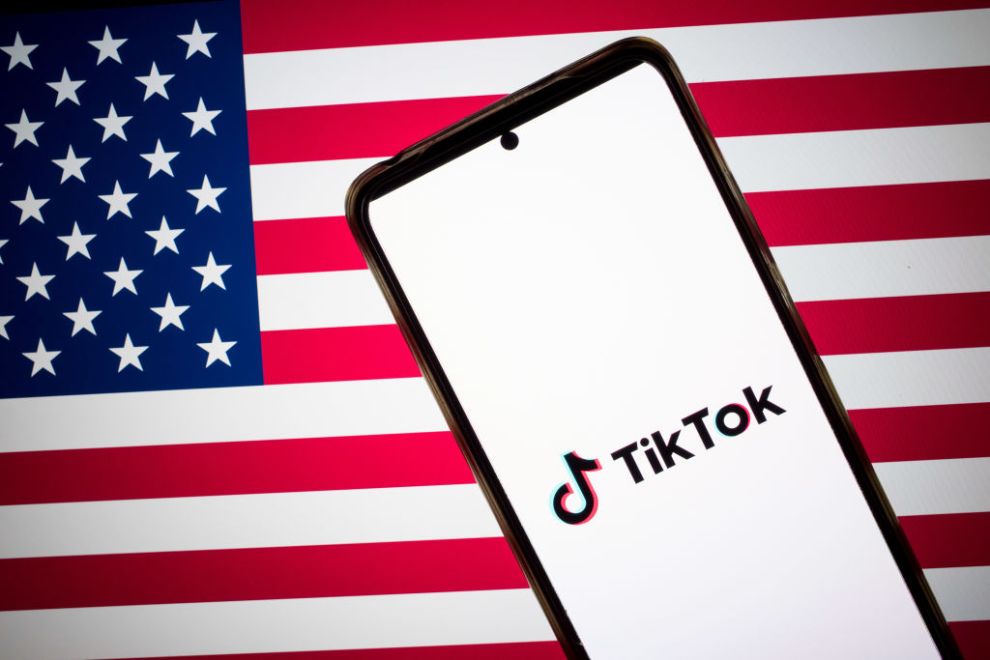 The TikTok logo appears on a smartphone screen, and the flag of the United States is on a computer screen as the background in this photo illustration in Athens, Greece, on January 15, 2025.