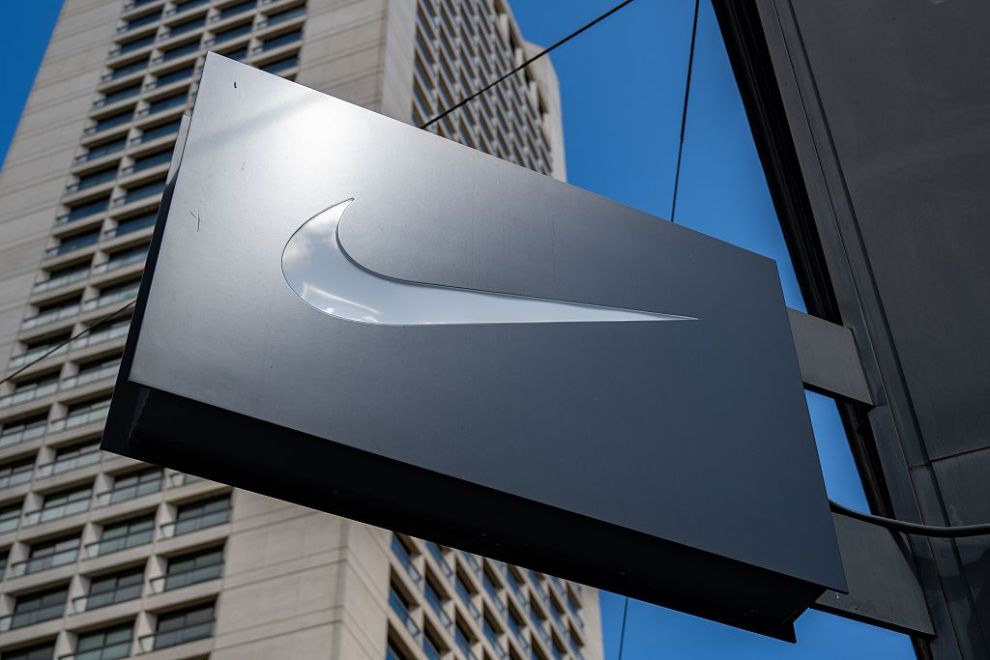 Projecting sign with Nike swoosh logo outside retail store against blue sky and high-rise buildings, San Francisco, California, May 13, 2025